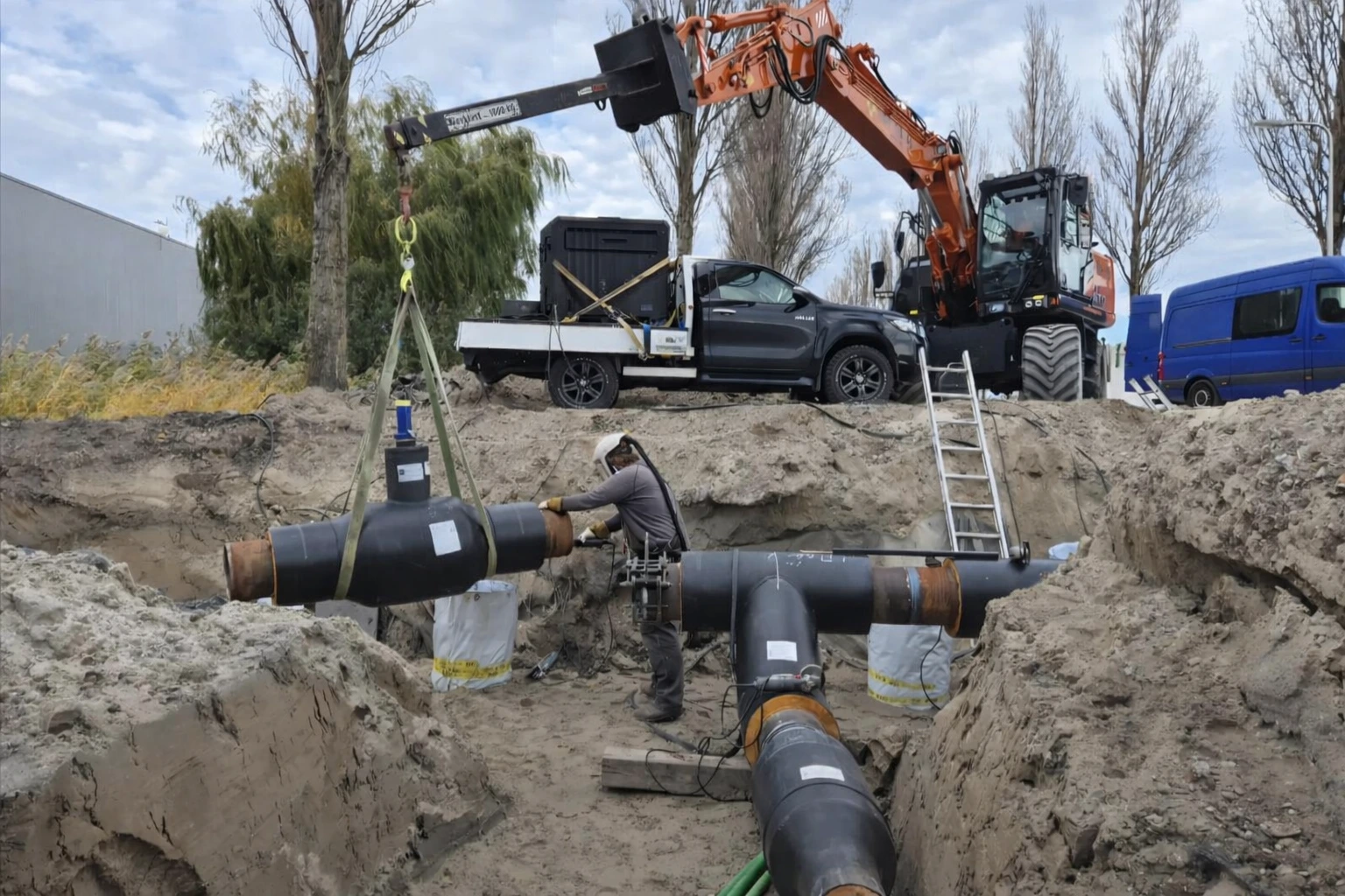 Ondergrondse leiding-installatie in een sleuf met graafmachine op de achtergrond